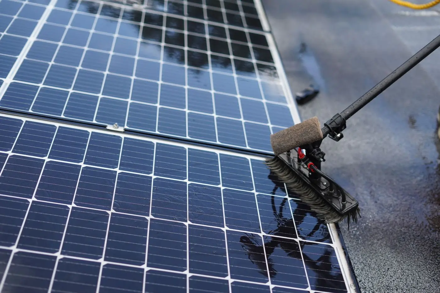 Close-up of a water-fed brush cleaning wet solar panels
